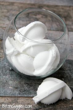 a glass bowl filled with white cream on top of a wooden table