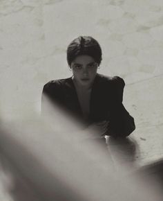 black and white photograph of a woman sitting at a table with her hand on her chest