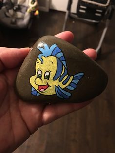 a hand holding a rock with an image of a fish on it