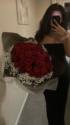 a woman taking a selfie while holding a bouquet of roses and a cell phone