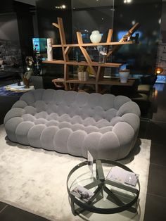 a large gray couch sitting on top of a white floor next to a glass table