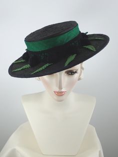 What a fun hat! Part Gaucho, part boater, it's a classic shape that never goes out of style. Black Straw is topped with a Kelly green band and double bow, a pretty lacy black trim around the crown, vintage fern leaves and black pom poms around the brim. Edged in black dupioni silk. Inner adjustable grosgrain ribbon and small comb in front help keep it anchored to the head. Such a fun look!Adjustable inner grosgrain ribbon headband for comfort and to keep the hat free from soil. Fits a 21 inch to Straw Boater Hat, Fun Hat, Straw Boater, Fern Leaves, Crown Vintage, Ribbon Headbands, Boater Hat, Dupioni Silk, Double Bow