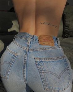 the back of a woman's jeans with a tattoo on her left side and words written in cursive writing