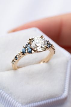 a close up of a person holding a ring on a white cloth with blue stones