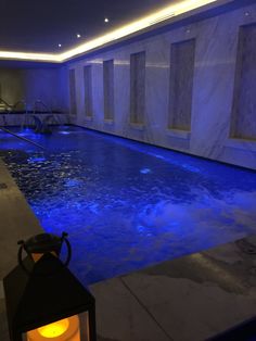 the indoor swimming pool is lit up with blue lights