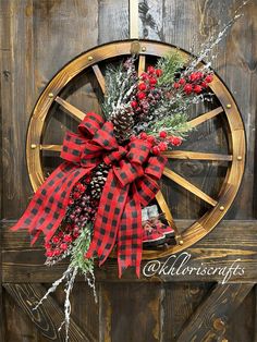 a christmas wreath with pine cones and red berries on a wagon wheel door hanger