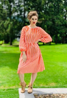 "Vintage 1970s Vuokko orange striped summer lightweight 100% cotton peasant style dress with elastic neckline; it's a loose straight dress with side seam pockets and self-belt. No flaws. Measurements laid flat Bust:26\" ( 52\") Hips:29\" (58\") Length shoulder to hem: 44\" Condition, excellent, cleaned. Models Measurements: Bust - 32\" Waist - 26\" Shoulders - 15\" Hips - 35 1/2\" Height - 5'8\" History of this pattern: Vuokko's stripes were an immediate sensation. In 1956, Marimekko introduced the iconic Jokapoika (\"Everyboy\") shirt as their first garment for men. Over the years, Vuokko has designed more than 300 colorways for \"Piccolo\" to be used for the shirts, from her original Mediterranean-inspired palette to black on white and everything in between." Spring Knee-length Midi Dress With Vertical Stripes, Vintage Orange Midi Dress For Summer, Vintage Orange Midi Dress For Spring, Orange Cotton Midi Dress For Daywear, Spring Cotton Dresses With Vertical Stripes, Knee-length Spring Dress With Vertical Stripes, Spring Knee-length Dress With Vertical Stripes, Spring Orange Cotton Midi Dress, Retro Striped Spring Dresses