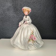 a ceramic figurine of a woman in a white dress with flowers on it