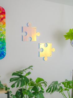 two pieces of puzzle are on the wall next to a potted plant and a clock