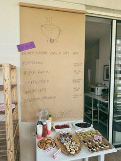 a table topped with lots of food next to a wall covered in writing on it