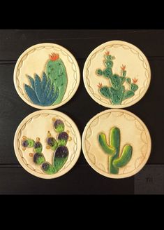 four ceramic plates decorated with cactus and succulents on black table top next to each other