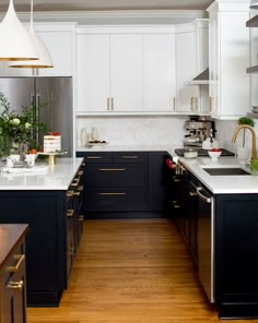 a kitchen with black cabinets and white counter tops, gold trimmings on the doors