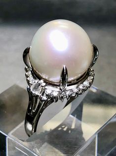 A classically designed cocktail ring done in platinum and centered by a genuinely beautiful South Sea pearl with a beautiful even luster and color measuring 14.50mm. Surrounding the central pearl is .46cttw in round and baguette diamonds ranging G-I in color and Vs1-Si1 in clarity. Diamond weight is stamped inside the shank. Dimensions/Weight: Ring measures .70" in diameter and weighs 12.6g. Size 8 (sizable). Condition: All stones are secure and in perfectly wearable condition. R-GJSYE Classic Oval Pearl Ring With Halo Setting, Formal White Gold Ring With Pearl Drop, Formal Silver Pearl Drop Ring, Classic Oval Pearl Ring With Center Stone, Formal Brilliant Cut Pearl Ring In Platinum, Formal Round Pearl Drop Ring, Formal White Gold Pearl Ring, Classic Round Pearl Ring With High Luster, Classic White Gold Pearl Ring In Platinum