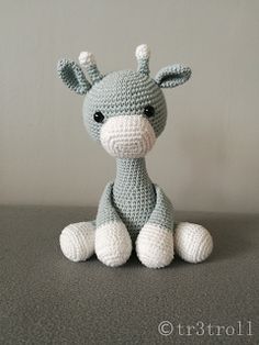 a crocheted giraffe sitting on top of a gray table next to a white wall