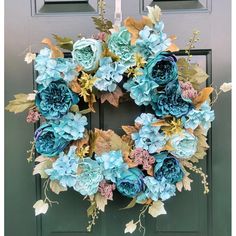 a wreath with blue flowers hanging on a door