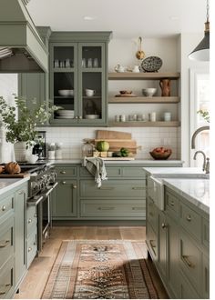 a kitchen with lots of green cabinets and white counter tops, an area rug on the floor