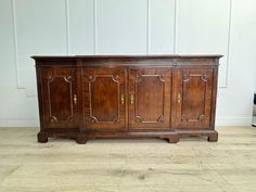 an old wooden sideboard sitting on top of a hard wood floor next to a wall