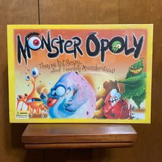 the board game monster opoly is displayed on a wooden shelf in front of a wall