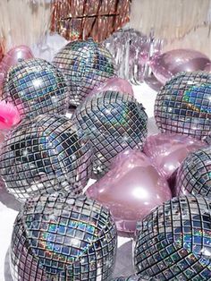 many shiny balls are sitting on a table with some pink flowers in the middle one