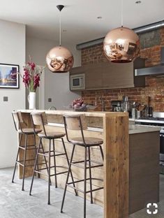 an image of a kitchen with bar stools in the center and two lights hanging from the ceiling