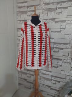 a white and red jacket on a mannequin stand in front of a brick wall