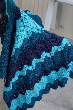 a crocheted blanket hanging on a clothes line in a room with white walls