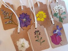 four tags with flowers on them hanging from string