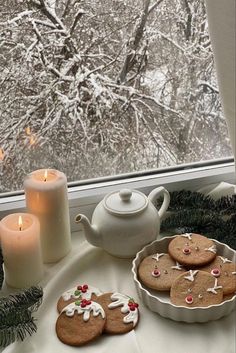 gingerbreads and cookies on a table near a window with snow covered trees in the background