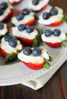 strawberries with cream cheese and blueberries on them are arranged on a white plate