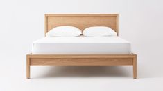 a bed with two pillows on top of it and a wooden frame around the headboard