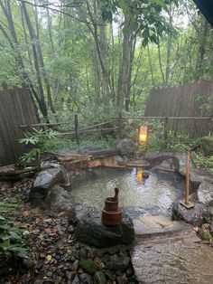 an outdoor hot tub surrounded by rocks and trees