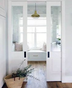 an open door leading to a bedroom with white walls and wood flooring, along with a window seat on the far side