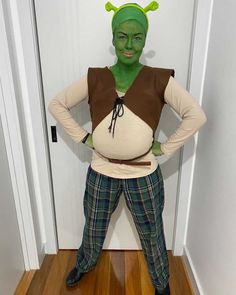 a man dressed up as the grinch in front of a door with his hands on his hips