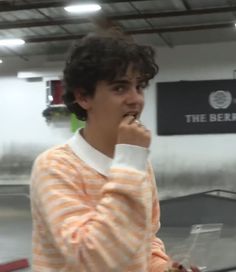 a young man standing in an airport holding his hand to his mouth and looking at the camera