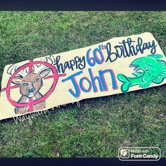 a sign that says happy 60th birthday john with a fish and deer on it sitting in the grass