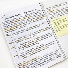 an open notebook with yellow sticky notes attached to the pages, on top of a white surface