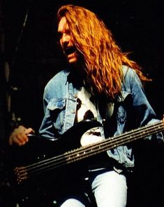 a man with long hair playing a bass