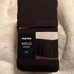 two folded black bed sheets on top of a white sheeted bed with text reading marttex ruffled bedskirt