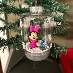 a glass ornament with a minnie mouse in it on top of a christmas tree