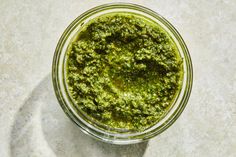 a glass bowl filled with pesto on top of a table