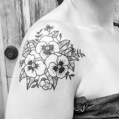 a black and white photo of a woman's shoulder with flowers tattooed on it