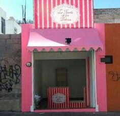 a pink and white building with a clock on it's side in front of graffiti covered walls