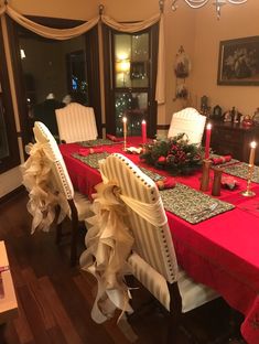 a dining room table set for christmas with candles and decorations on the tablescloths