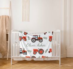 a baby crib with a red tractor on it and the name oliver asher written in white