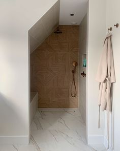 a bathroom with a shower, towel rack and wooden door in the wall next to it