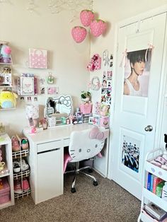 a white desk topped with a computer monitor next to a wall covered in pink decorations