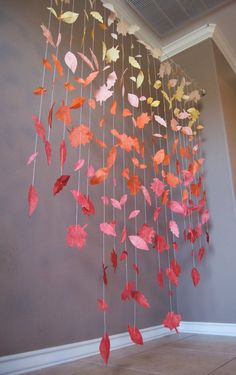 a wind chime with red and yellow leaves hanging from it's sides in a room