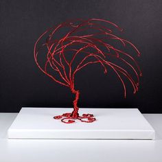 a red wire tree sitting on top of a white box