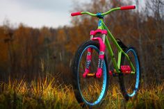 a pink and green bike parked in the grass