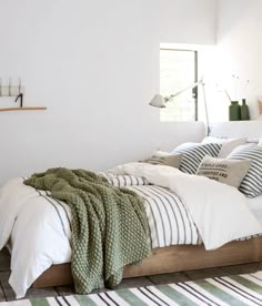 a bedroom with white walls and striped rugs on the floor next to a bed